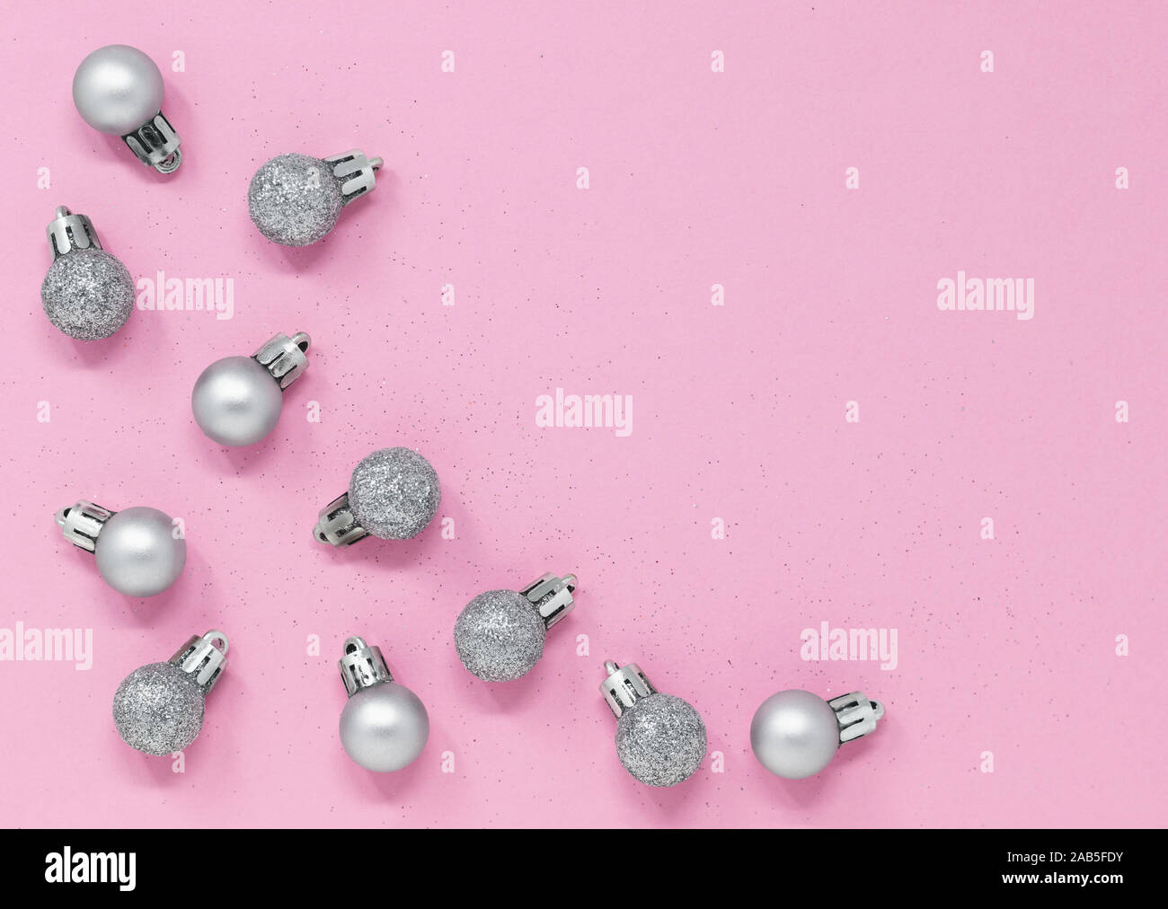 Glänzendes Silber Weihnachtskugeln Grenze auf einem rosa Hintergrund. Minimale flach Komposition mit Kopie Raum Stockfoto