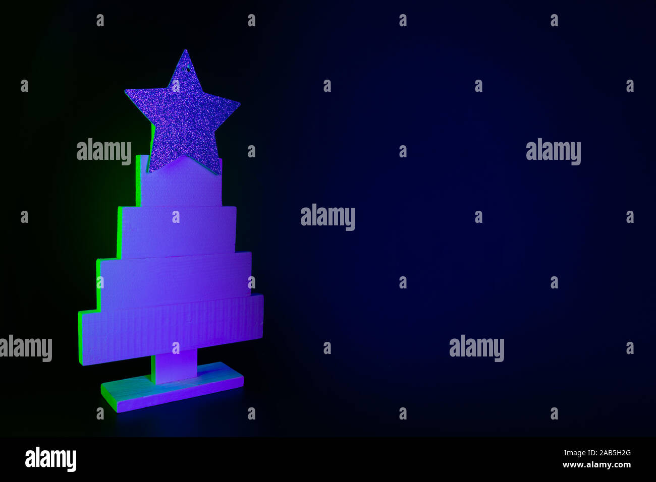 Weihnachtsbaum in Neon Blau und Grün auf Schwarz. Kreative Muster mit Platz für Text und Urlaubswünsche. Xmas Party Hintergrund. Stockfoto