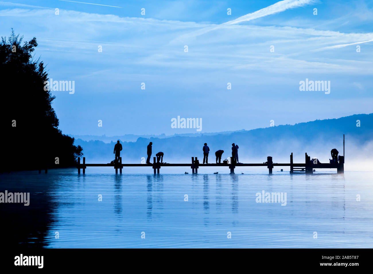 Viele Menschen, sterben im Morgengrauen Sport aufeinem Bootssteg am Starnberger See machen Stockfoto