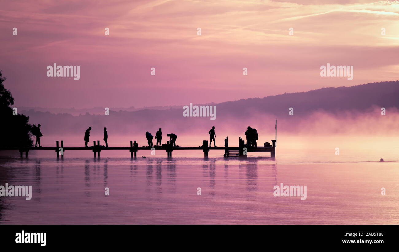 Viele Menschen, sterben im Morgengrauen Sport aufeinem Bootssteg am Starnberger See machen Stockfoto