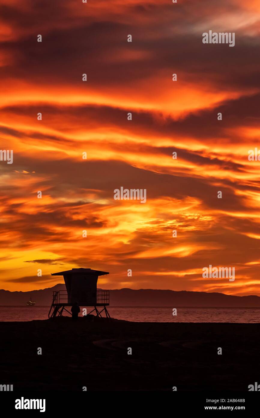 Helles orange dramatischer Sonnenuntergang mit Lifeguard tower Silhouette Stockfoto