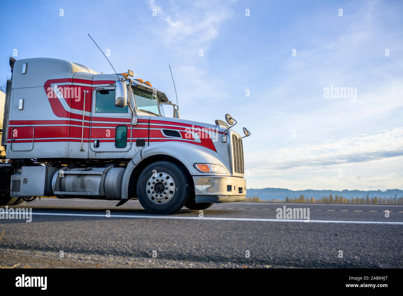 Klassische weiße und rote Amerikanische Big Rig Semi Truck mit niedrigem Dach Transport flüssiger Ladung in Edelstahl Tank semi Trailer läuft auf der Geraden Stockfoto