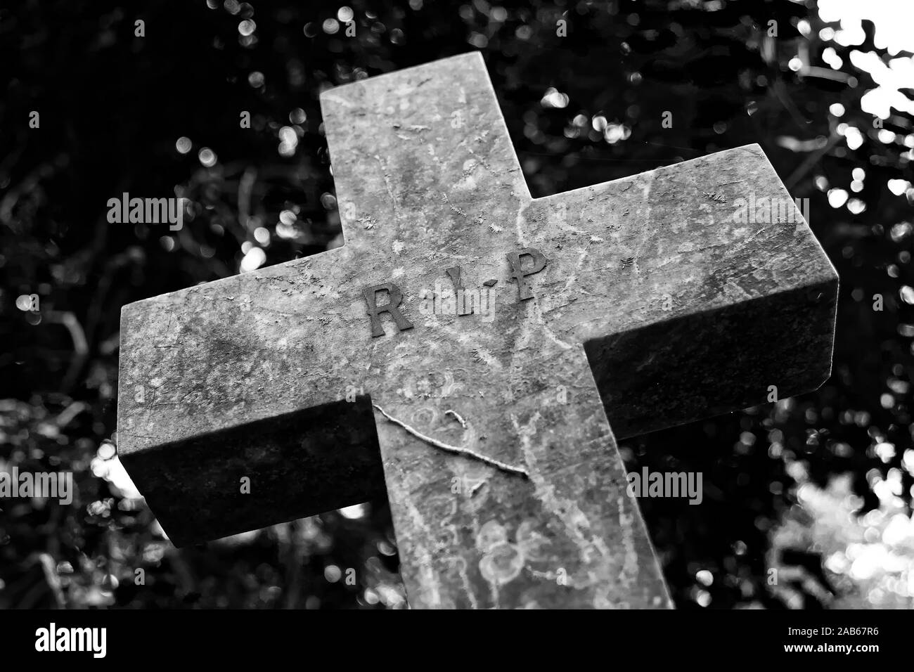 Ein wonky steinernes Kreuz auf einem Friedhof mit r.i.p Zeichen eingraviert Stockfoto