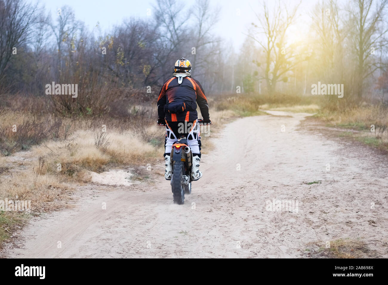 Sport und Aktiv gesund leben Konzept. Der Motorradfahrer in den späten Herbst Wald. Reiten auf Motorrad an einem sonnigen Tag unter vielen Bäumen. Stockfoto