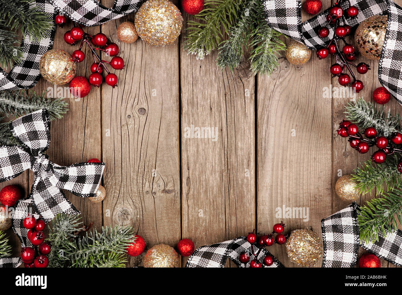 Weihnachten Rahmen mit den weißen und schwarzen überprüft Buffalo plaid Farbband, Kugeln und Zweigen. Ansicht von oben auf eine rustikale Holz Hintergrund. Stockfoto