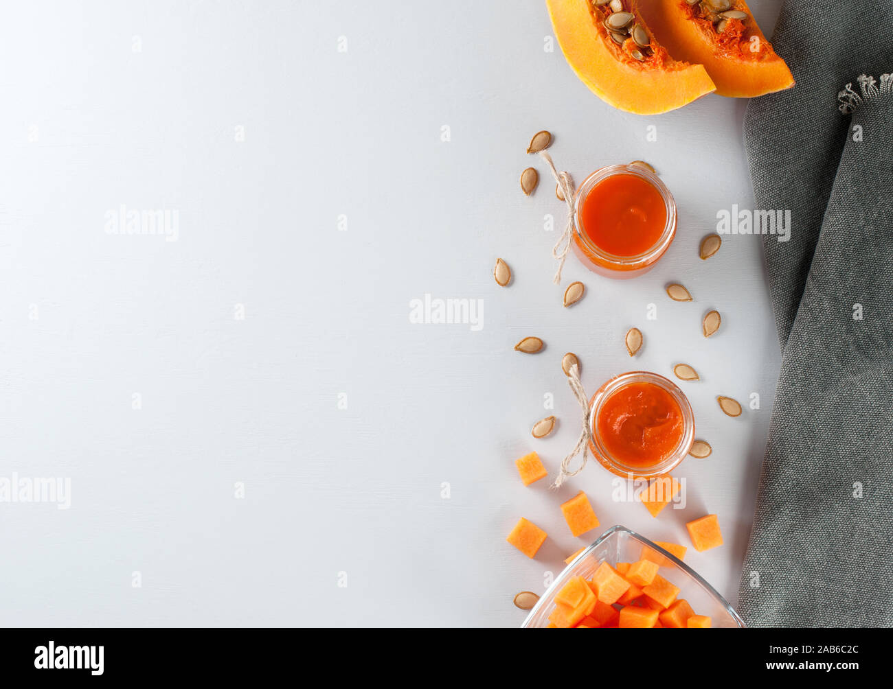 Frische Kürbis Marmelade in Gläser auf dem grauen Hintergrund mit Kürbiskernen verziert. Herbst Rezepte aus einem Kürbis. Gesunde Ernährung Konzept. Flach, horizo Stockfoto