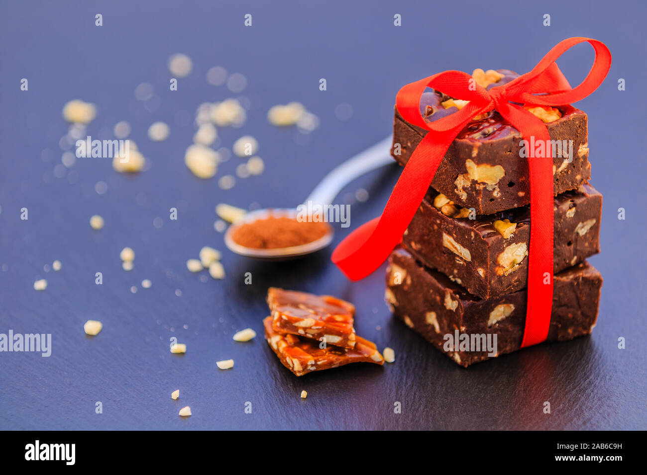 Hausgemachte Schokolade und Karamell mit Erdnüssen und Kakao auf schwarzem Hintergrund. Stockfoto