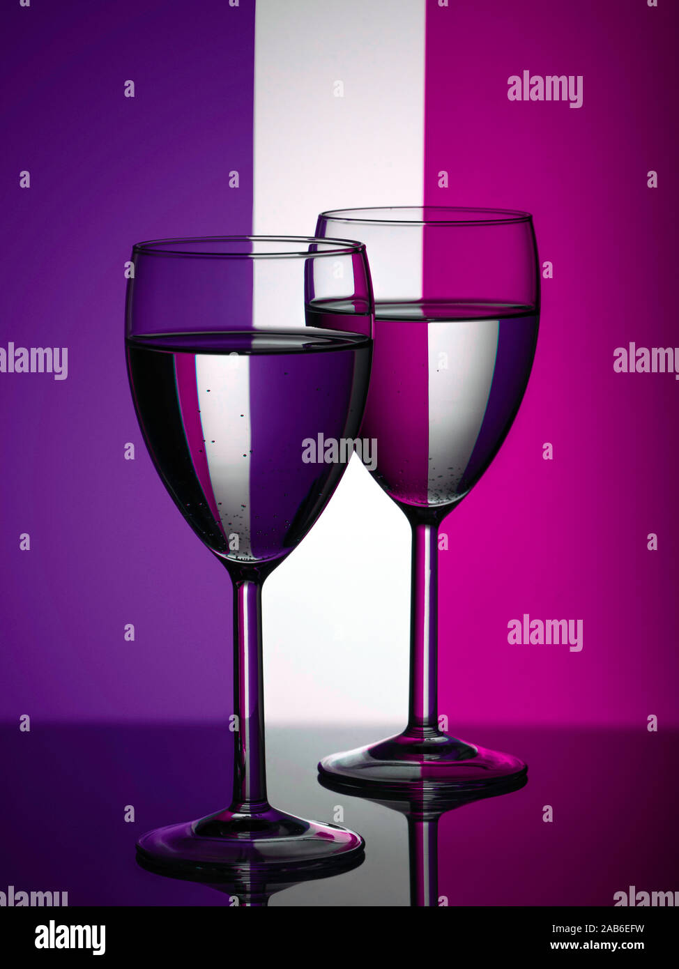 Zwei Weingläser silhouette voll auf farbigem Hintergrund. Lila und violett Streifen im Hintergrund. Alkohol trinken. Stockfoto