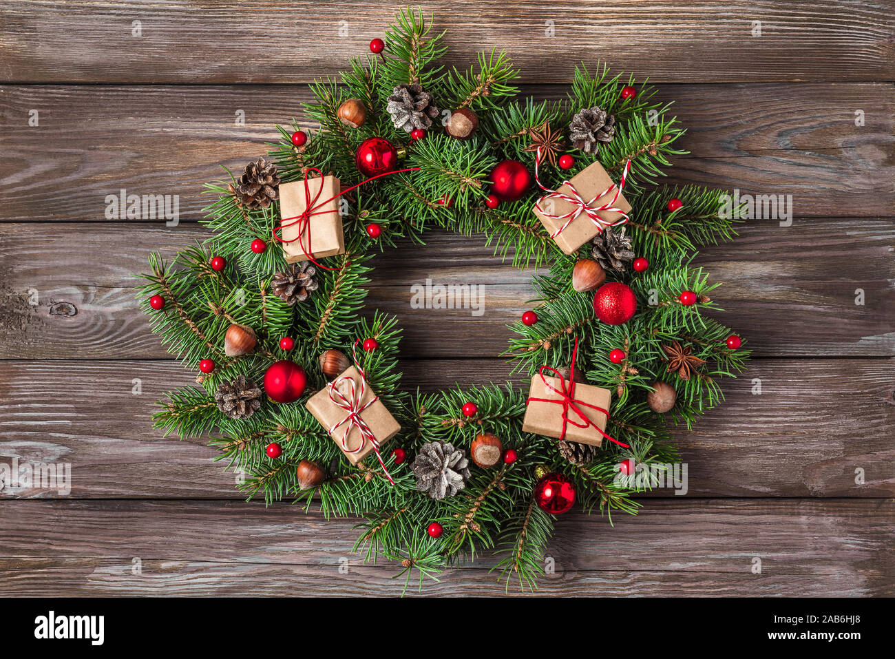 Weihnachten Kranz aus Zweigen Tanne, rot Dekorationen, Geschenkboxen, Tannenzapfen auf Holz- Hintergrund. Weihnachten, Winter, neues Jahr. Wohnung La Stockfoto