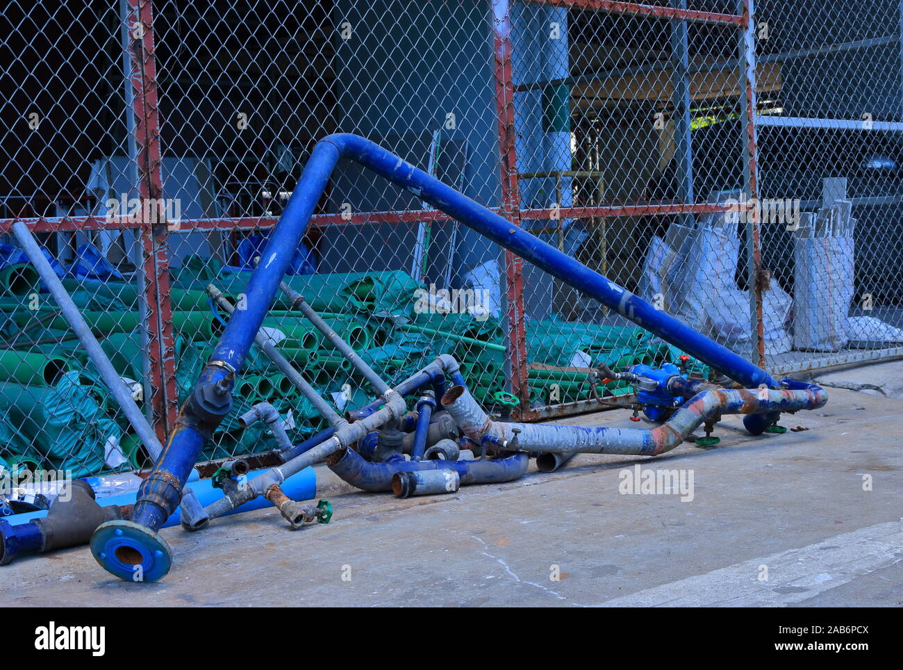 Closeup aufgegeben 90-Grad-Biegung Wasserleitung lehnte sich gegen den Zaun des Lagers, Warten auf Recycling Stockfoto