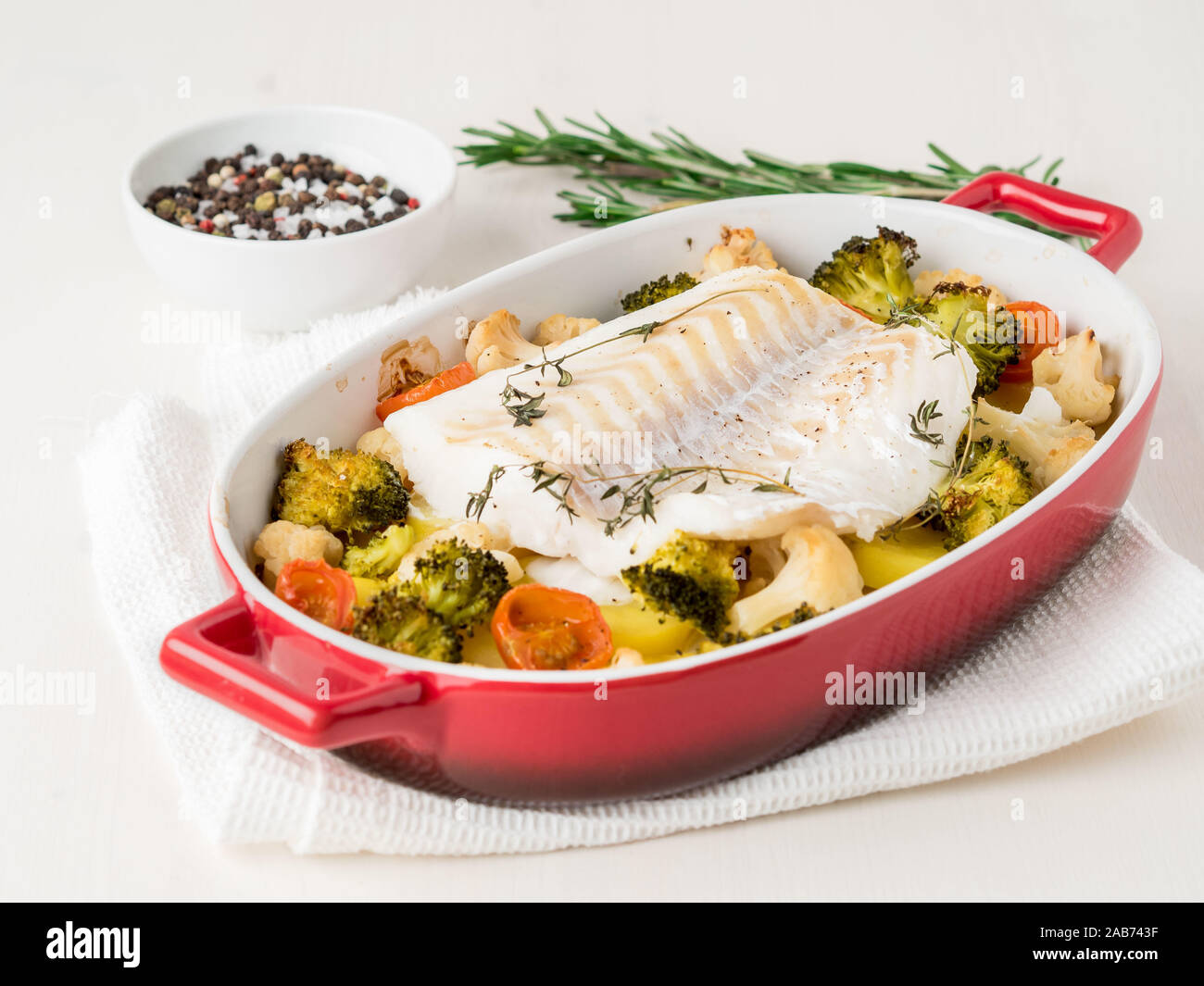 Kabeljau Fisch im Ofen gebacken mit Gemüse - Gesunde Ernährung Gesunde  Ernährung. Helle Holz- Hintergrund, Seitenansicht Stockfotografie - Alamy