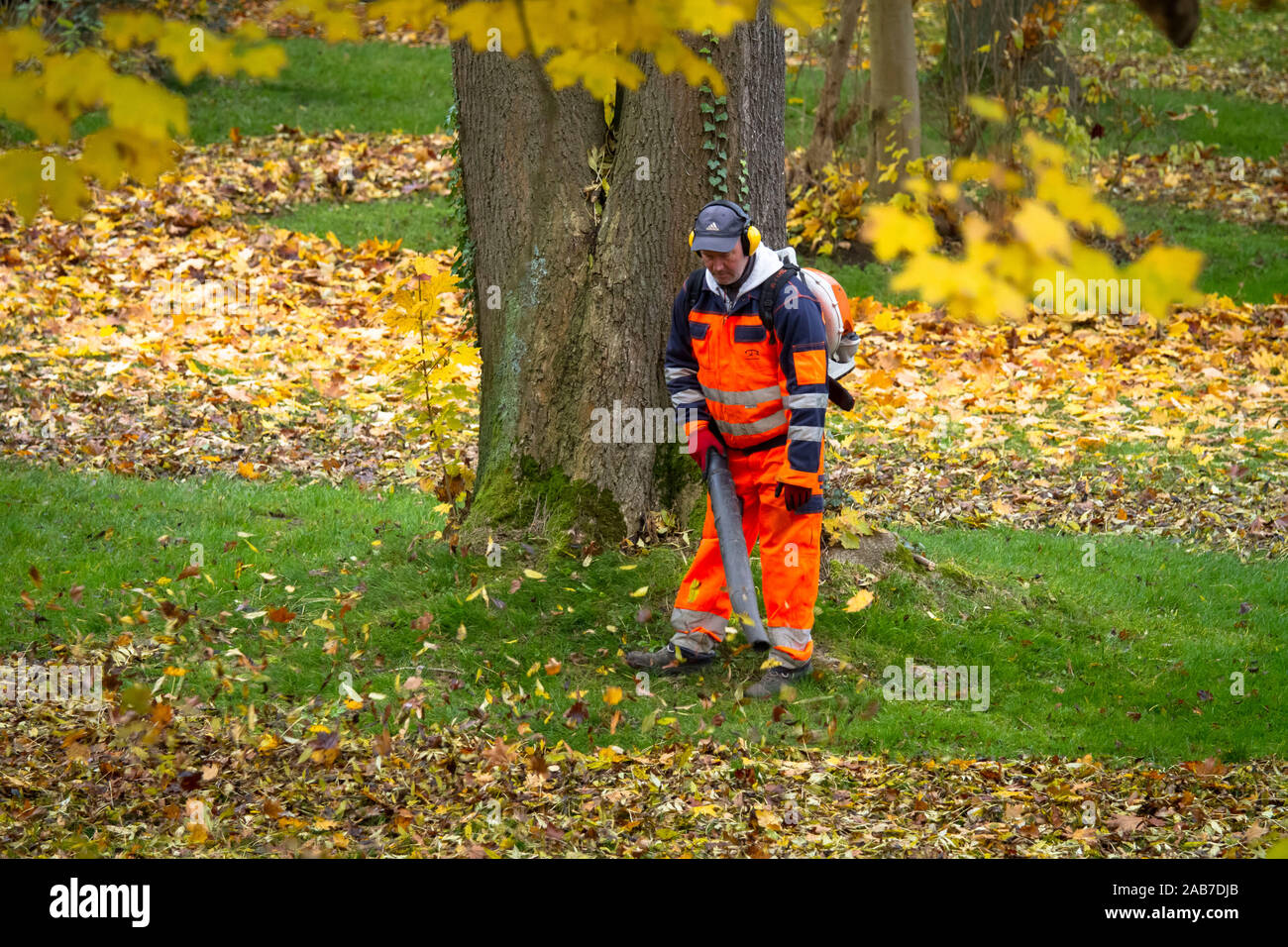 Arbeitnehmer mit einem Rucksack Laubbläser in einem öffentlichen Park in der Stadt Wetter, Nordrhein-Westfalen, Deutschland. Arbeiter mit einem Laubblaeser in einem o Stockfoto