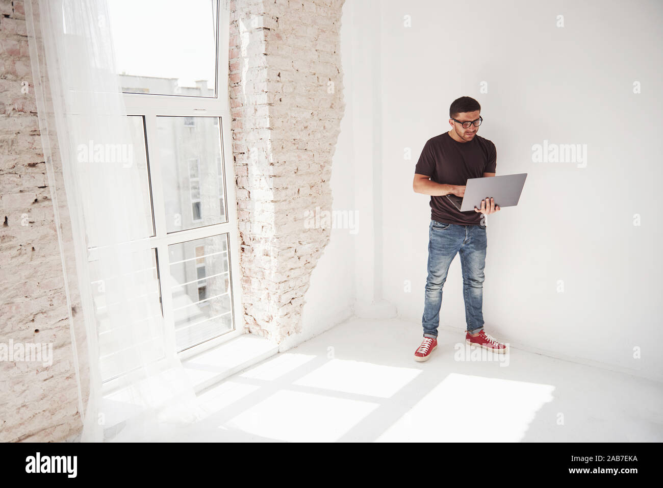 Hübscher junger Mann mit Laptop und seinen Zeitplan auf weißem Hintergrund prüfen Stockfoto