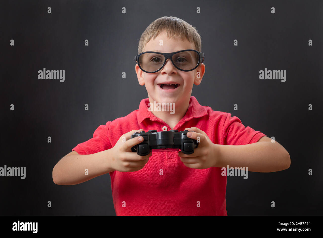 Der Junge lächelt mit 3 D-Brille und einem Gaming joypad in der Hand. Stockfoto