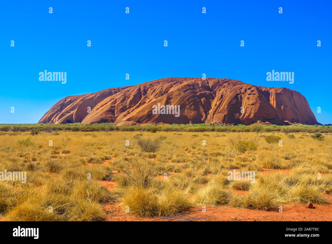 Roter Sand der australischen Outback zum Ayers Rock in der trockenen Jahreszeit, riesiger Monolith aus Sandstein im Uluru-Kata Tjuta National Park, UNESCO, Australien Stockfoto