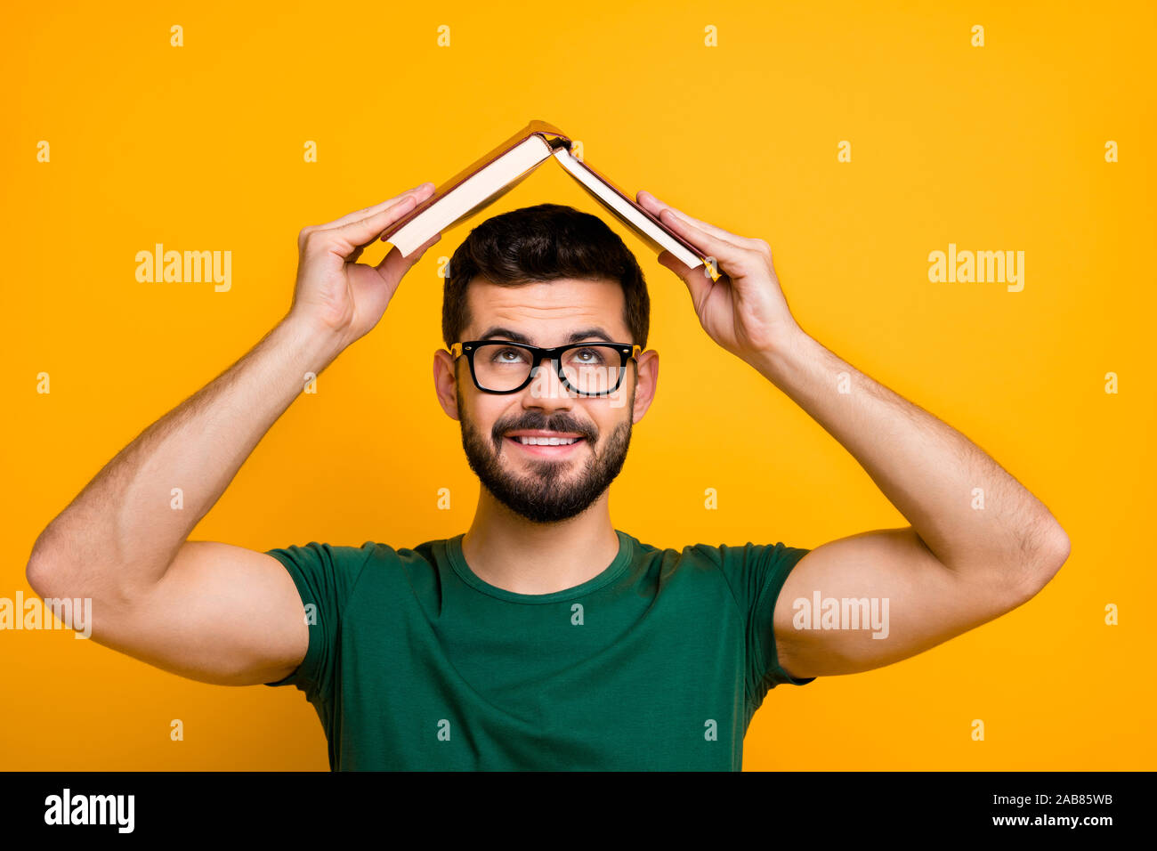 Nahaufnahme Foto von fröhlichen brunet Haar Kerl setzte Buch aus Papier über dem Kopf kreative lesen Konzept look Informationen tragen merken Brille moderne Stockfoto