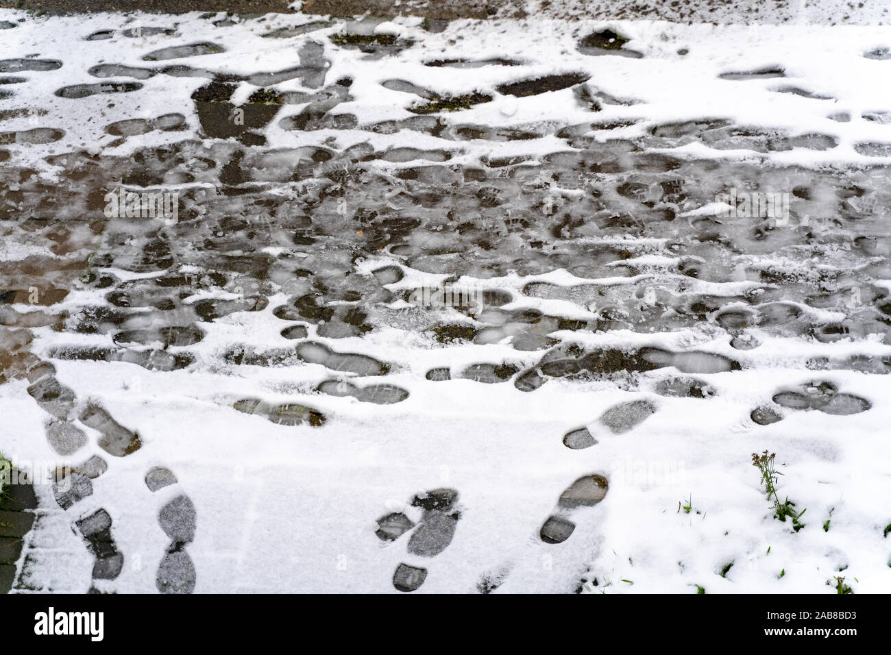 Der erste Schnee auf der Straße. Spuren auf dem verschneiten Pflaster. Winter Wetter Hintergrund Stockfoto