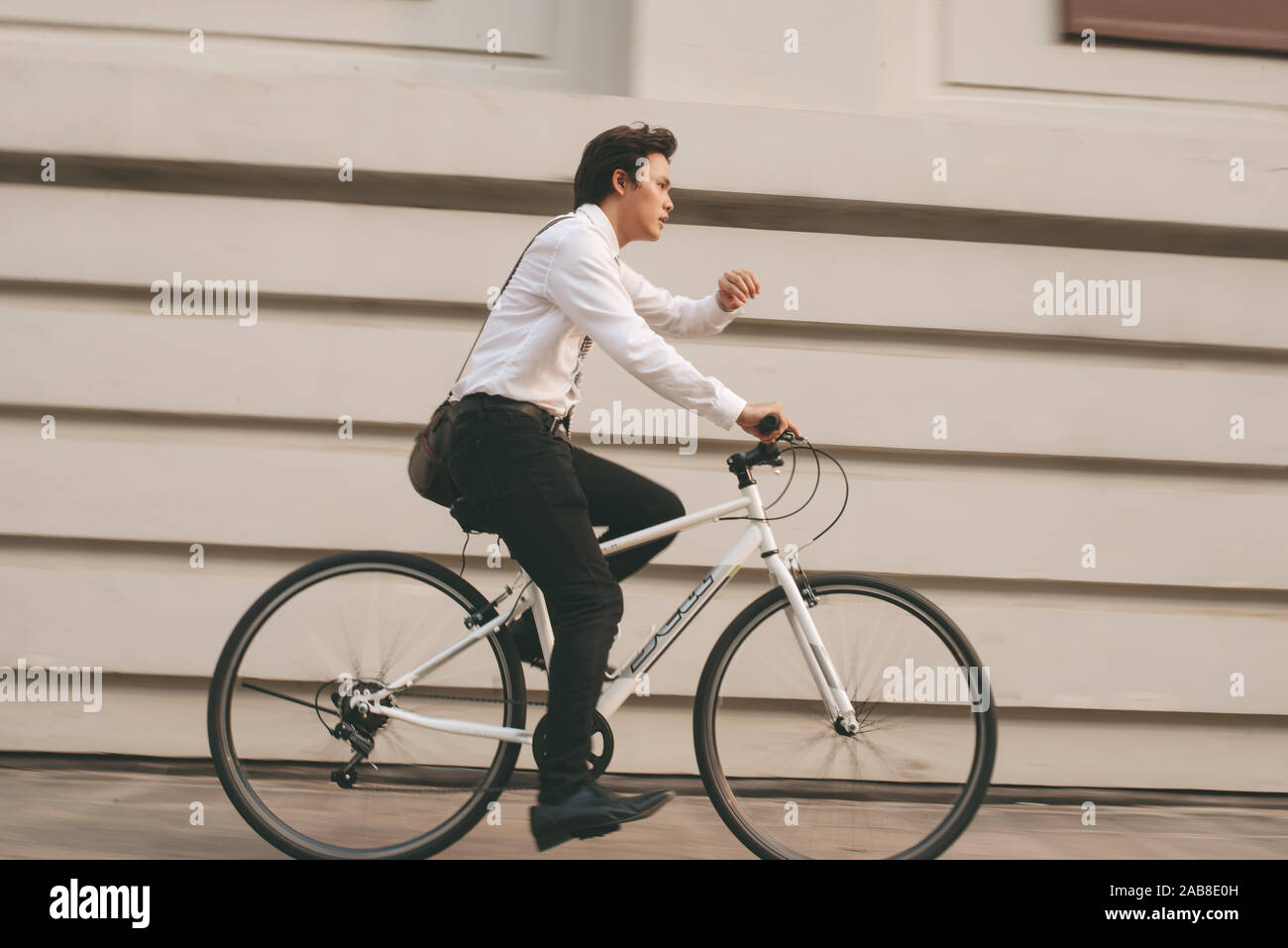 Beeilen Sie sich asiatische Geschäftsmann Reiten Fahrrad im Berufsverkehr. Junger Mann spät für Zug arbeiten, Konferenz. Büro Leben und Geschäft. Stockfoto
