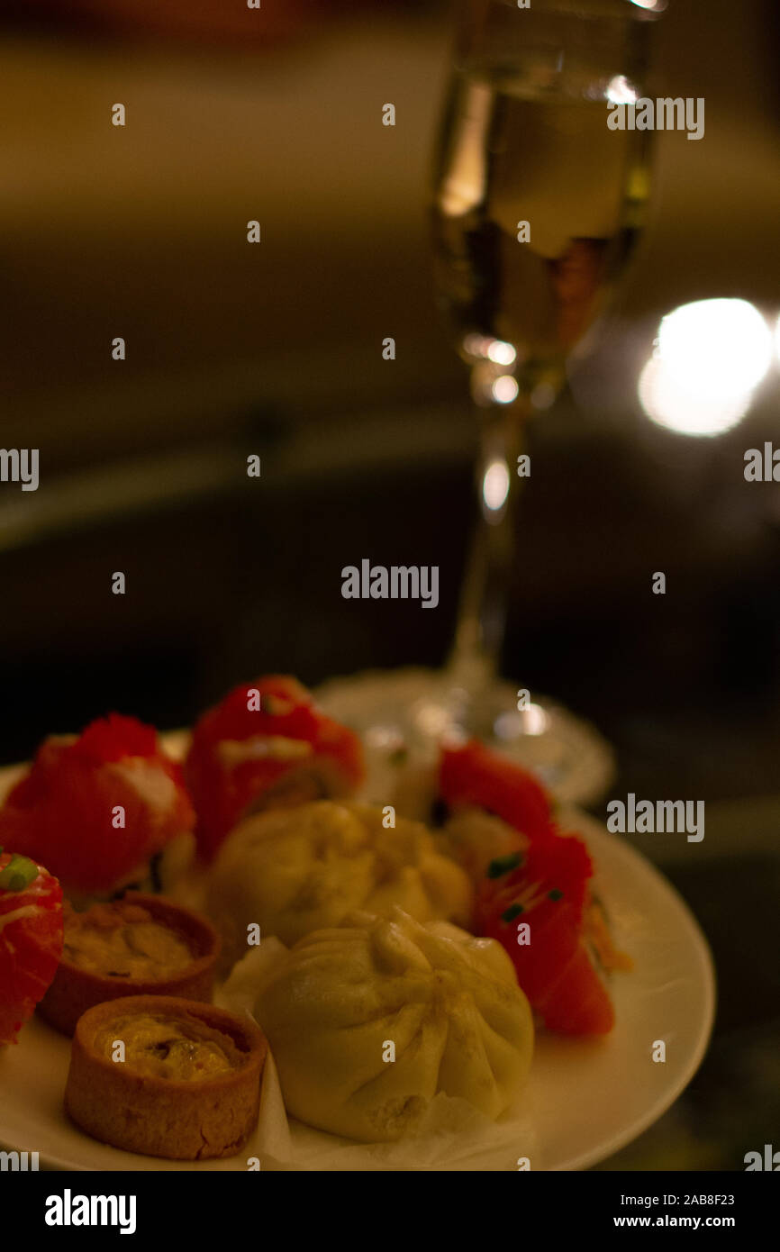 Fizzy Champagner Aperitif vor dem Abendessen Häppchen wie mini Quiches, chinesischen Brötchen und Sushi Stockfoto