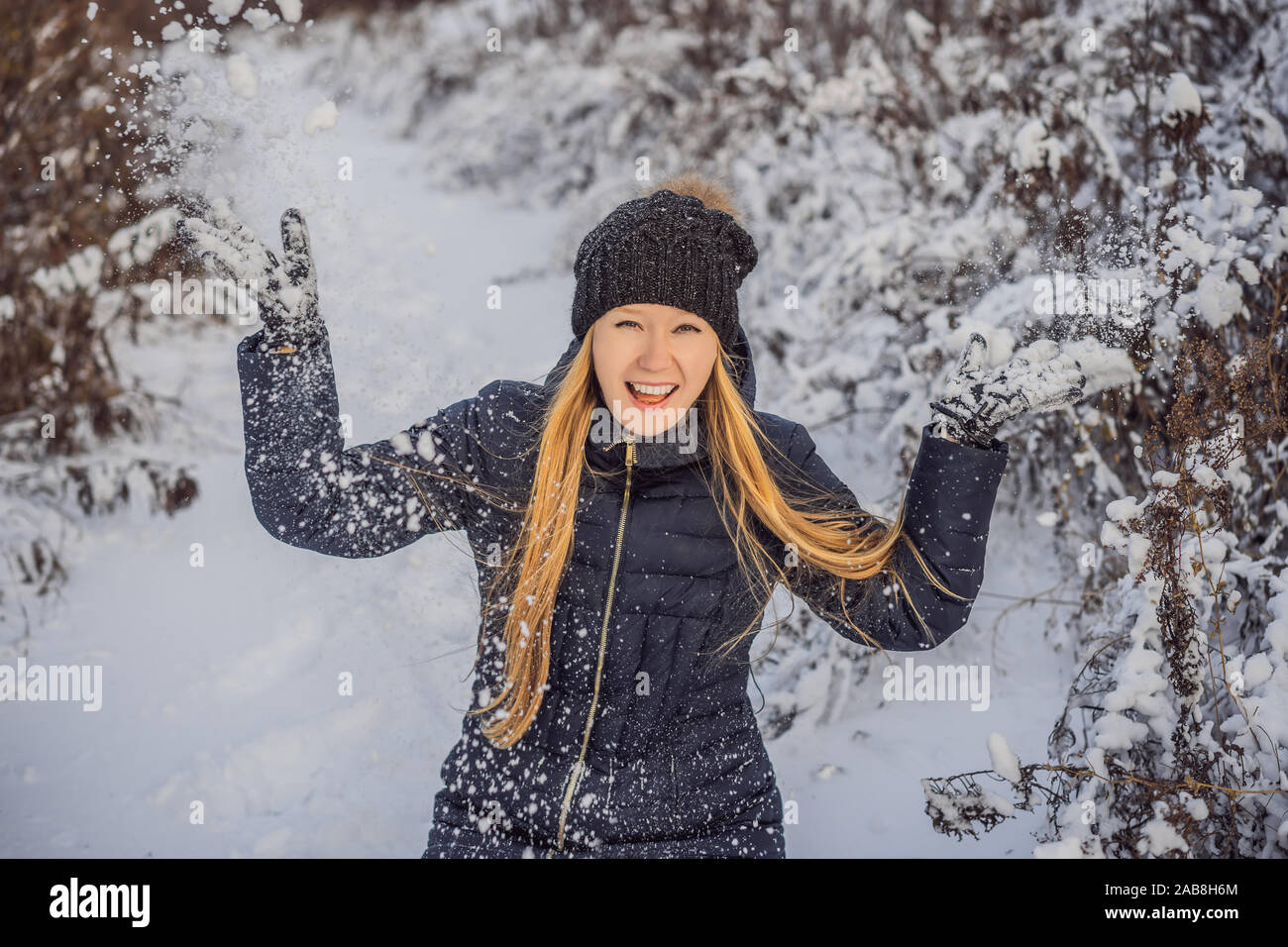 Frau hat Spaß im Winter, wirft Schnee Stockfoto