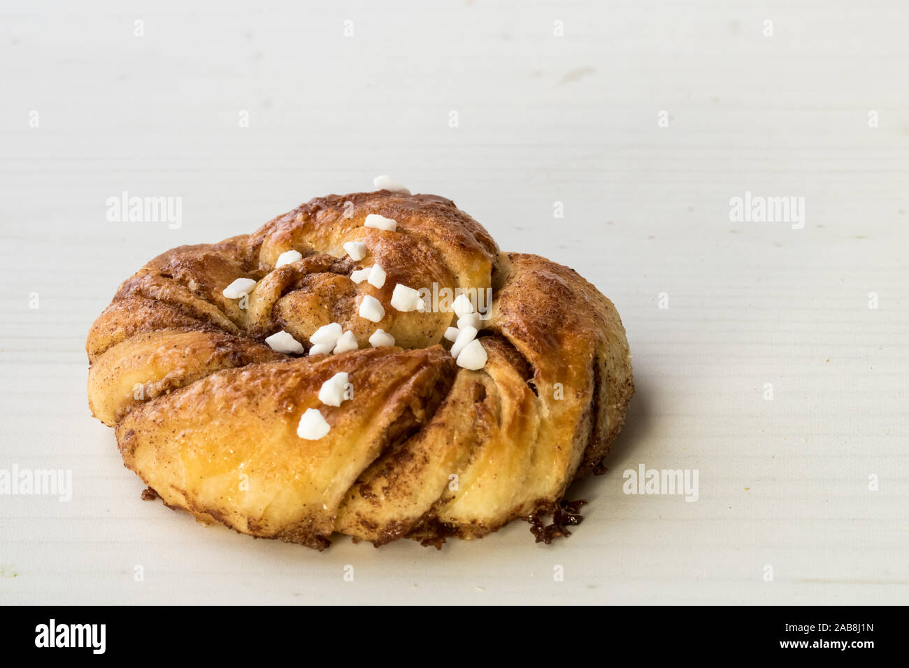 Eine Nahaufnahme eines verdrillten Schwedische Cinnamon Bun mit Perle Zucker fertig für den Verzehr. Stockfoto
