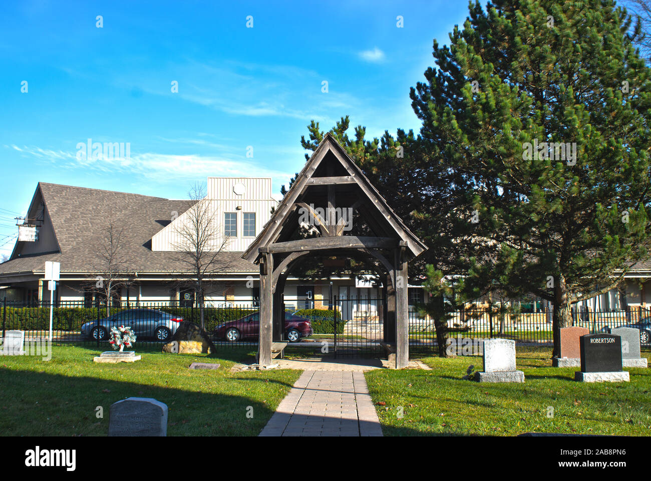 Eine Welle von Kirche und Friedhof ist auf der Website; ein Baum ist daneben; blauer Himmel. Stockfoto