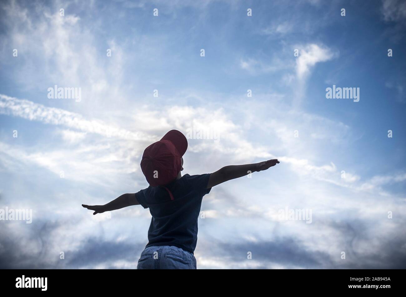 4 Jahre alter Junge vorgibt, über bewölkter Himmel zu fliegen. Kinder Phantasie Konzept zu fördern. Stockfoto