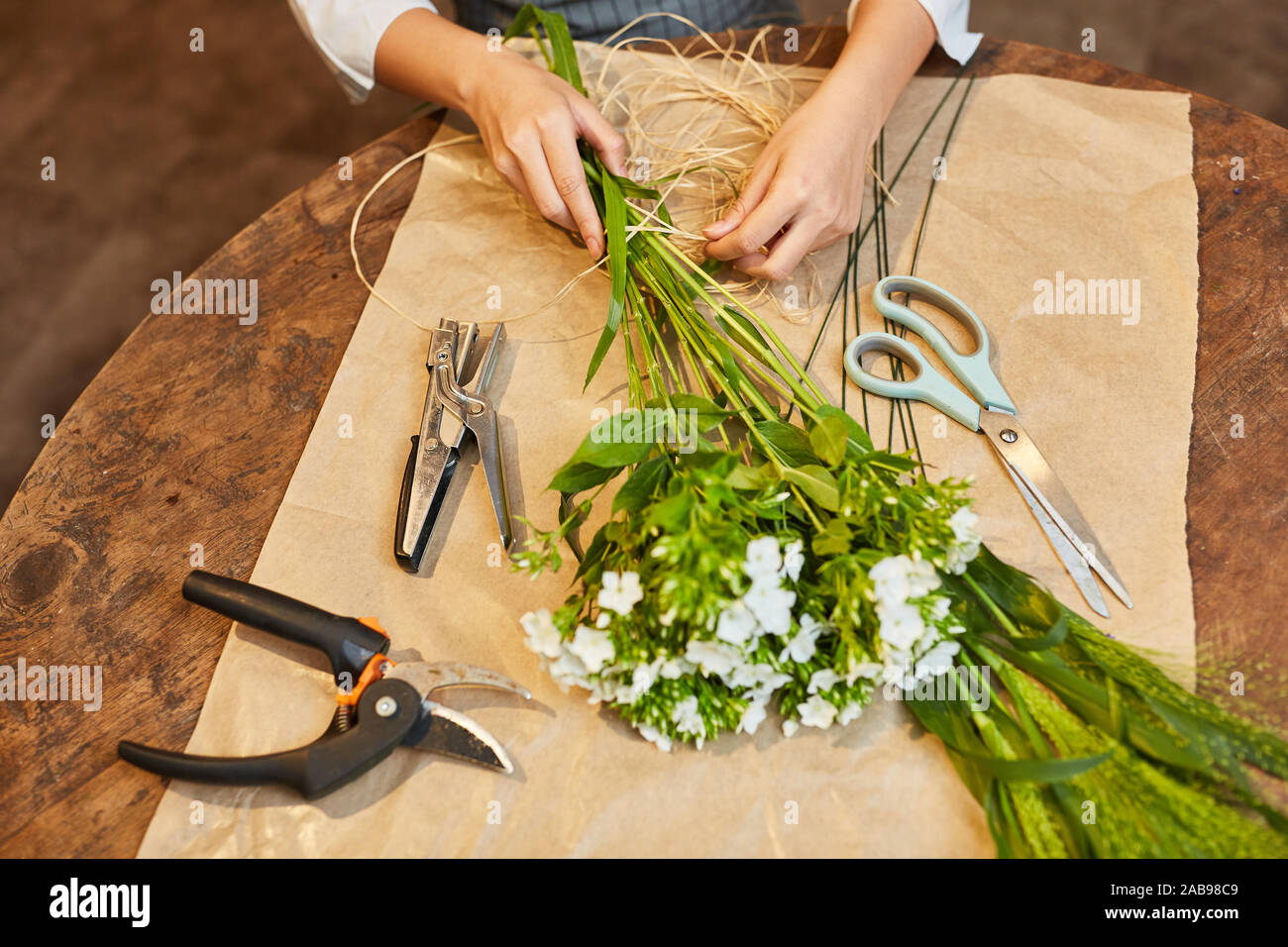 Hände von einem Floristen Blumen binden mit Bast für einen Blumenstrauß Stockfoto