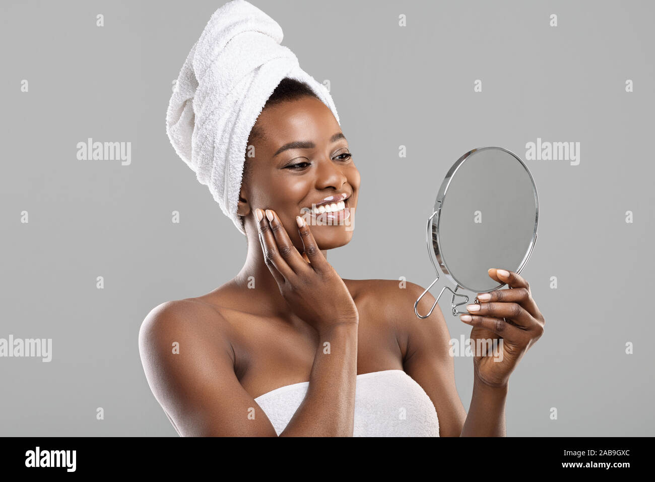 Schöne afrikanische Frau mit Spiegel und berühren ihre perfekte weiche Haut Stockfoto