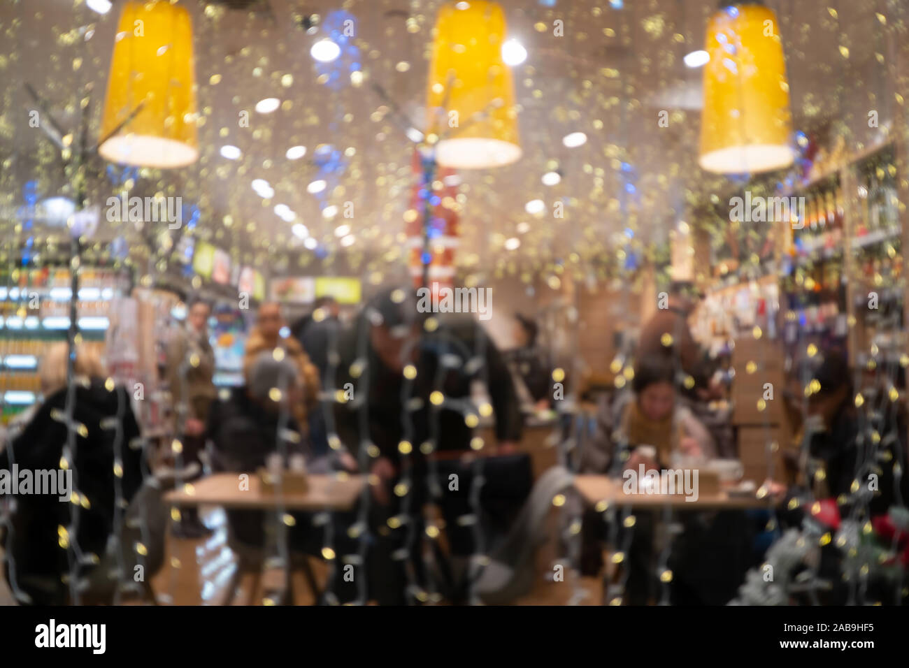 Menschen sitzen und essen in einem Cafe am Heiligen Abend. Verwischt Weihnachten Hintergrund Stockfoto