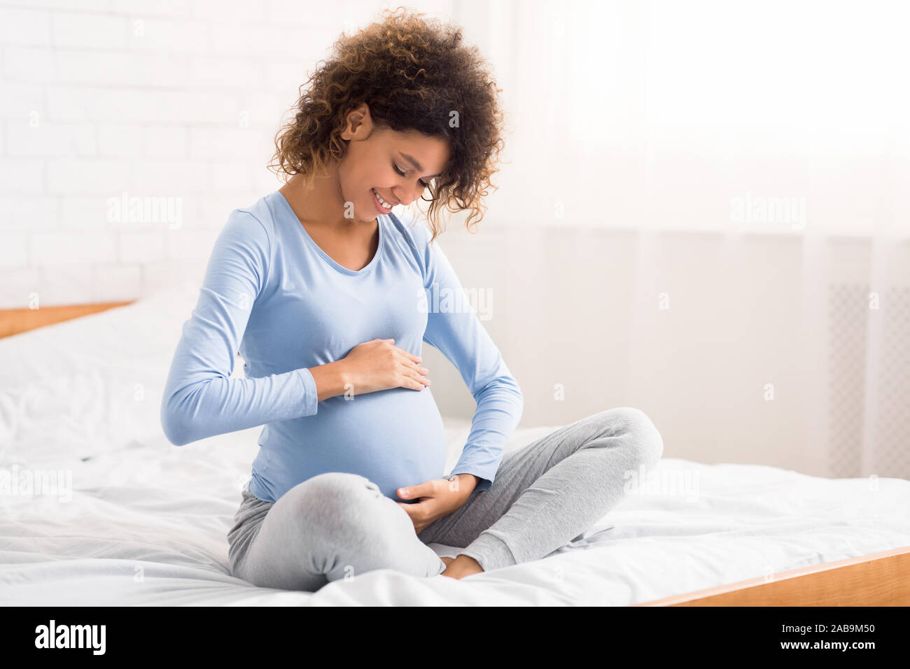 Ziemlich schwangere Frau ihren Bauch streicheln, Reden zu Ihrem Baby Stockfoto