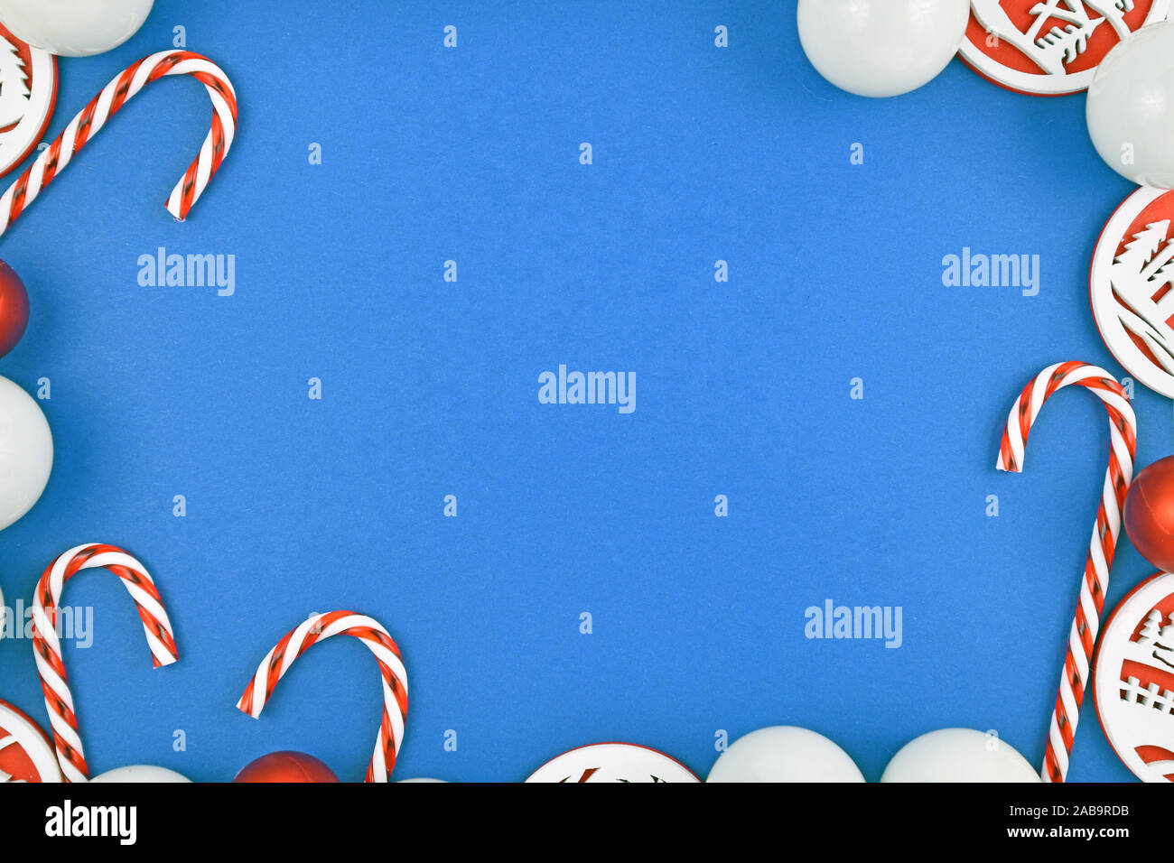 Weihnachten flach mit roten und weißen Christbaumschmuck wie Kugeln und Zuckerstangen bilden Rahmen um helle blaue Hintergrund Stockfoto