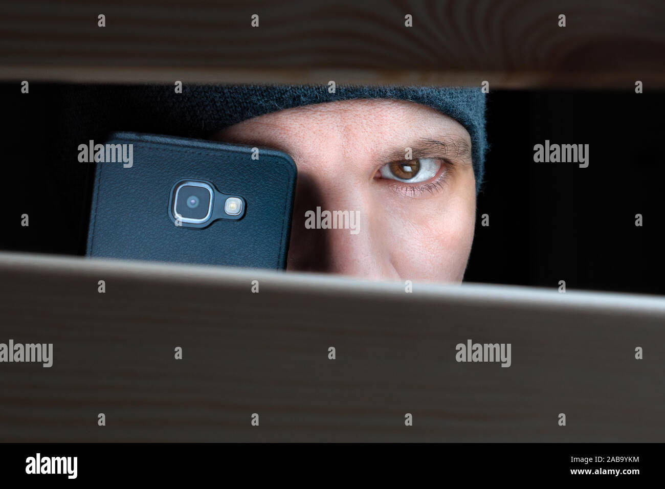 Informationen weitergeben. Um die Aufnahme zu einer versteckten Kamera auf Mobile. Privatdetektiv mit Kamera blickt auf eine Kluft. Spionage Hintergrund. Das Konzept der Lauschangriffe, Spionage, Klatsch und die gelbe Taste Stockfoto