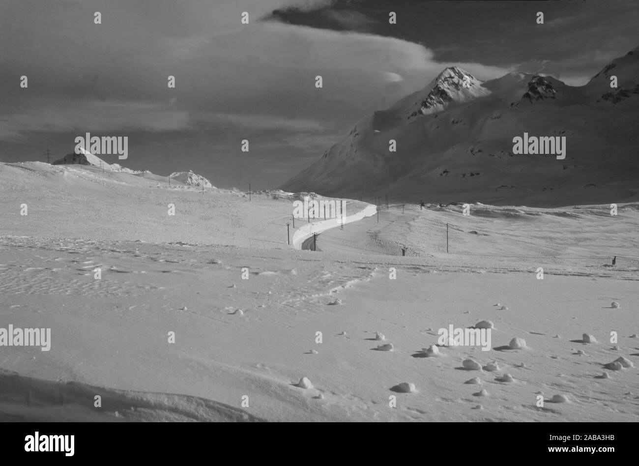 Die Rhätische Railyway mäanders im tiefen Schnee der Schweizer Alpen am Berninapass Stockfoto
