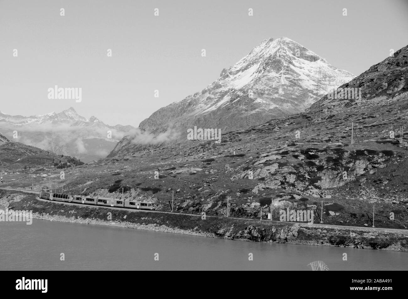 Unesco-Welterbe Train-Reise: Der Bernina-Train ist Kurvt durch die Schweizer Alpen am Gletscher See Bianco am Berninapass Stockfoto