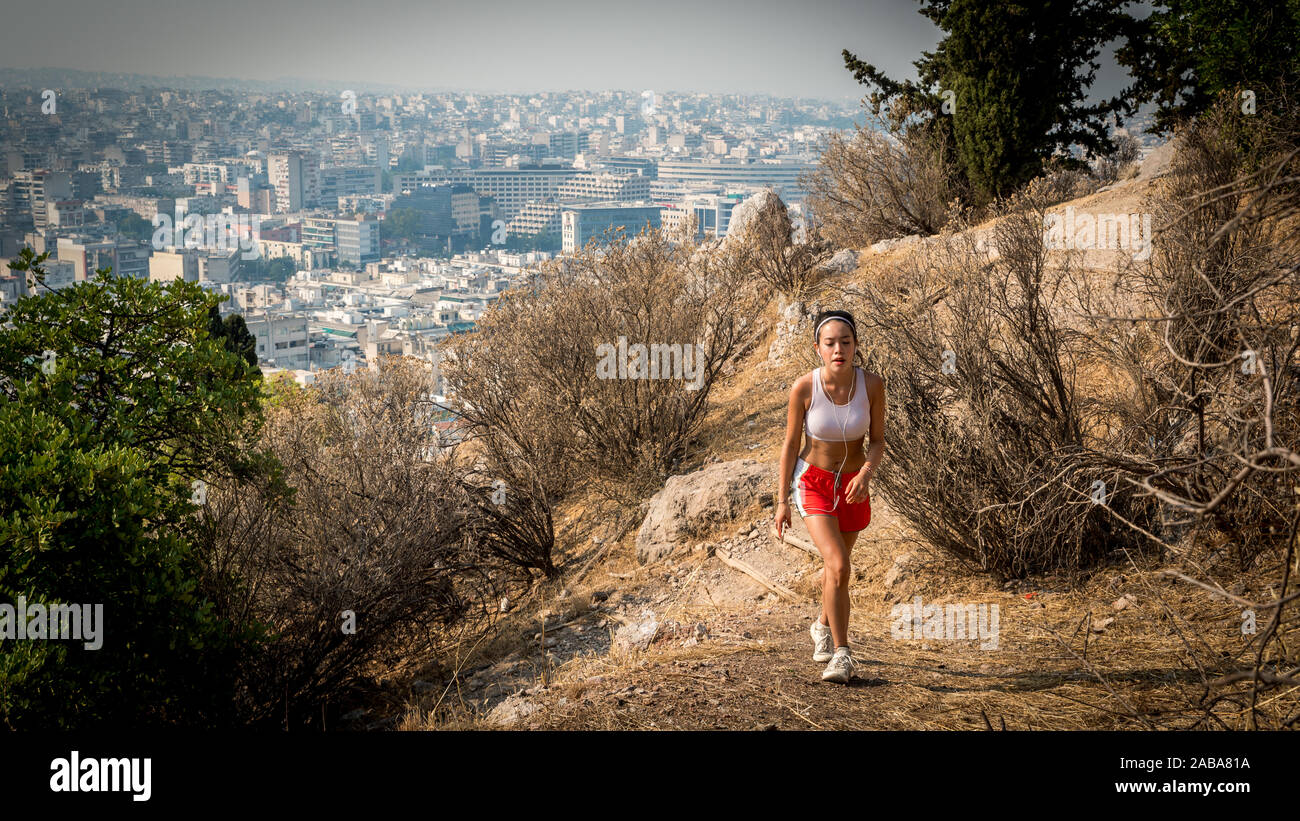 In roten Hosen und weißen Turnschuhen auf Trail auf den Berg mit der Stadt Athen im Hintergrund jugendlich Stockfoto