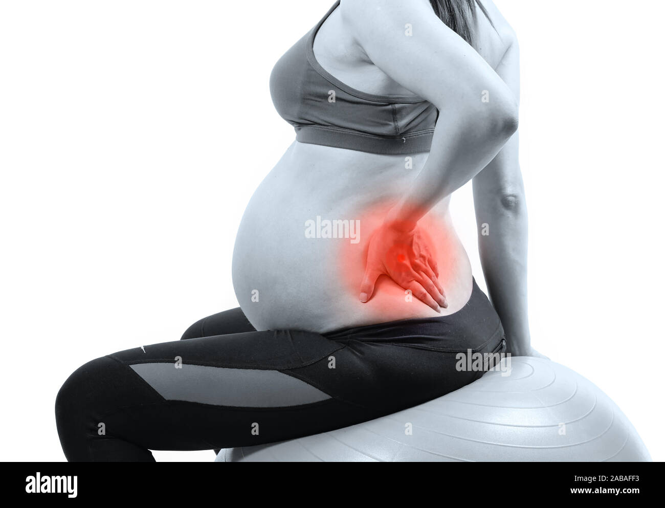 Schwangere Frau auf Gymnastikball Holding ihr zurück in den Schmerz Stockfoto