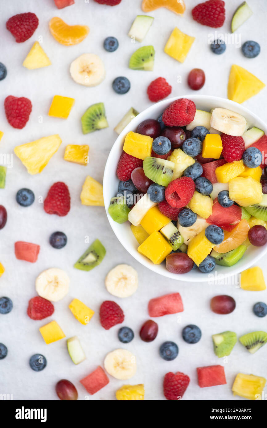 Schüssel, auf dem geschnittenes Obst auf einem weißen Hintergrund. Obst Himbeeren, Heidelbeeren, Bananen, Trauben, Mango, Ananas, Melone, Kiwi, Birne Stockfoto