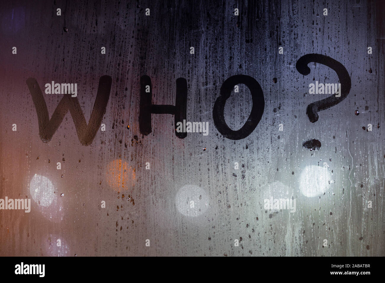 Die quaestion Wer mit dem Finger auf Nacht nasses Glas mit verschwommen Lichter im Hintergrund geschrieben. Stockfoto