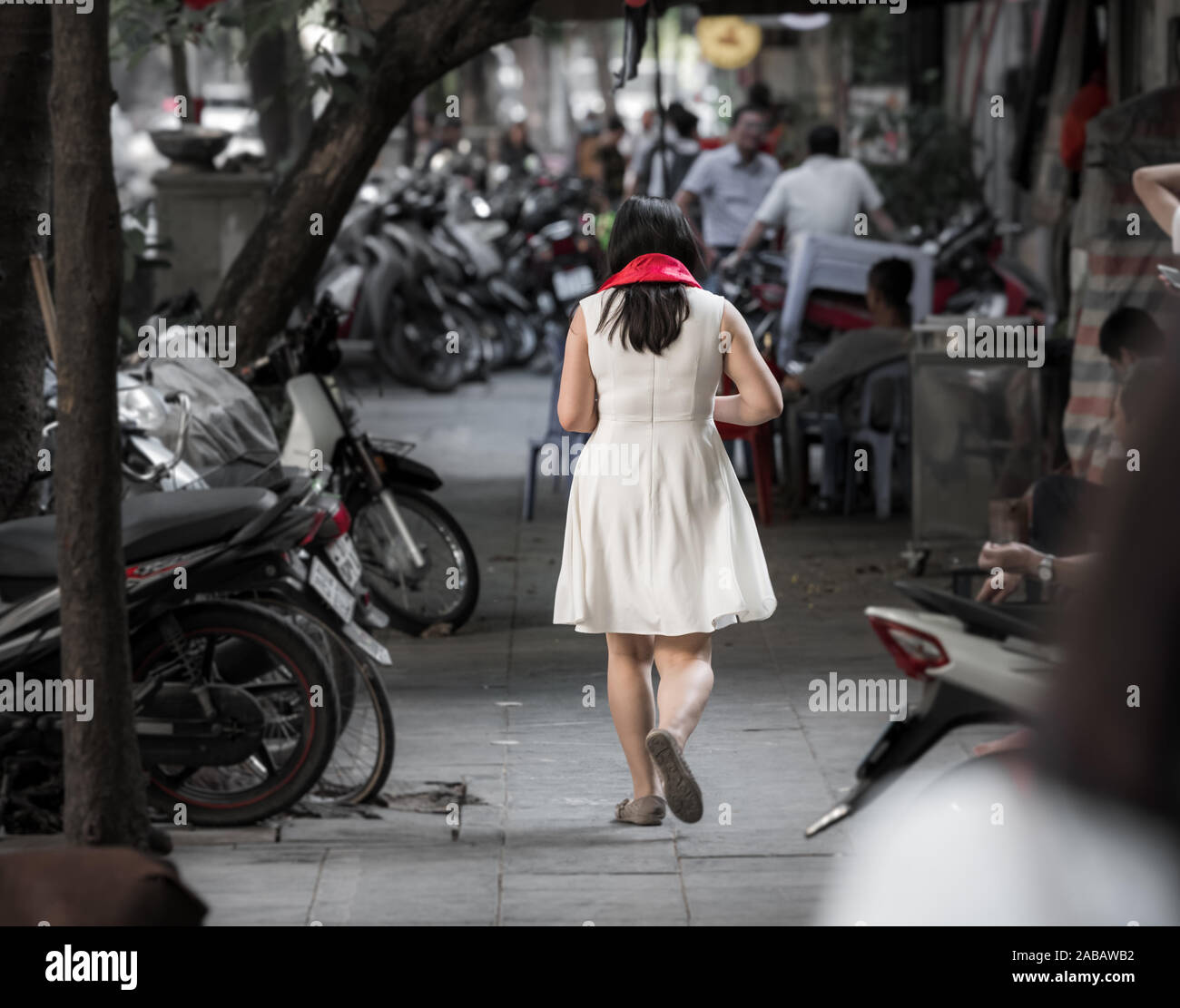 Eine asiatische Frau mit einem hellen roten Schal, als Geschenk zu Fuß durch die Straßen von Hanoi, Vietnam, Asien gekauft wurde Stockfoto