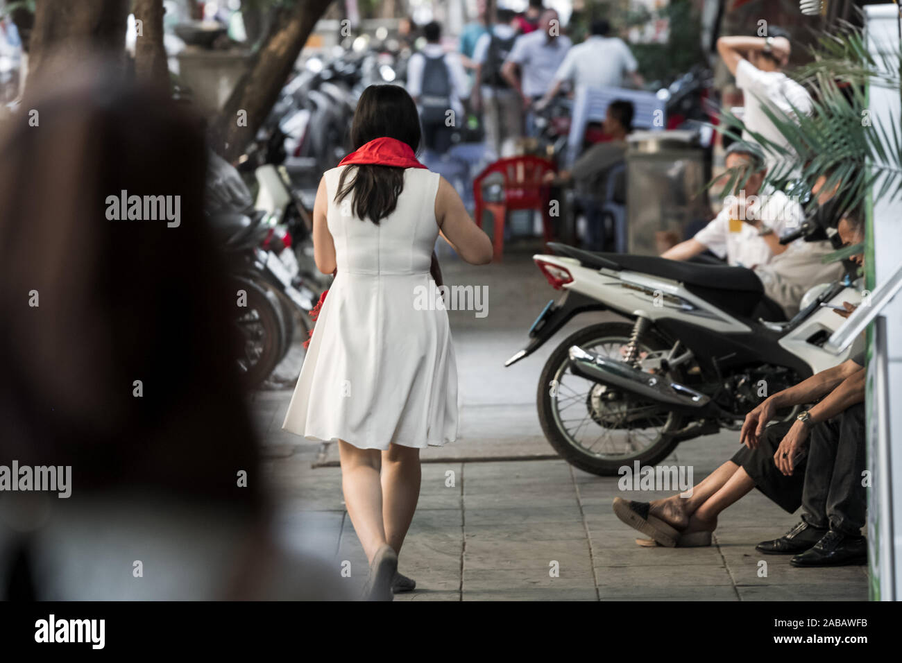 Eine asiatische Frau mit einem hellen roten Schal, als Geschenk zu Fuß durch die Straßen von Hanoi, Vietnam, Asien gekauft wurde Stockfoto