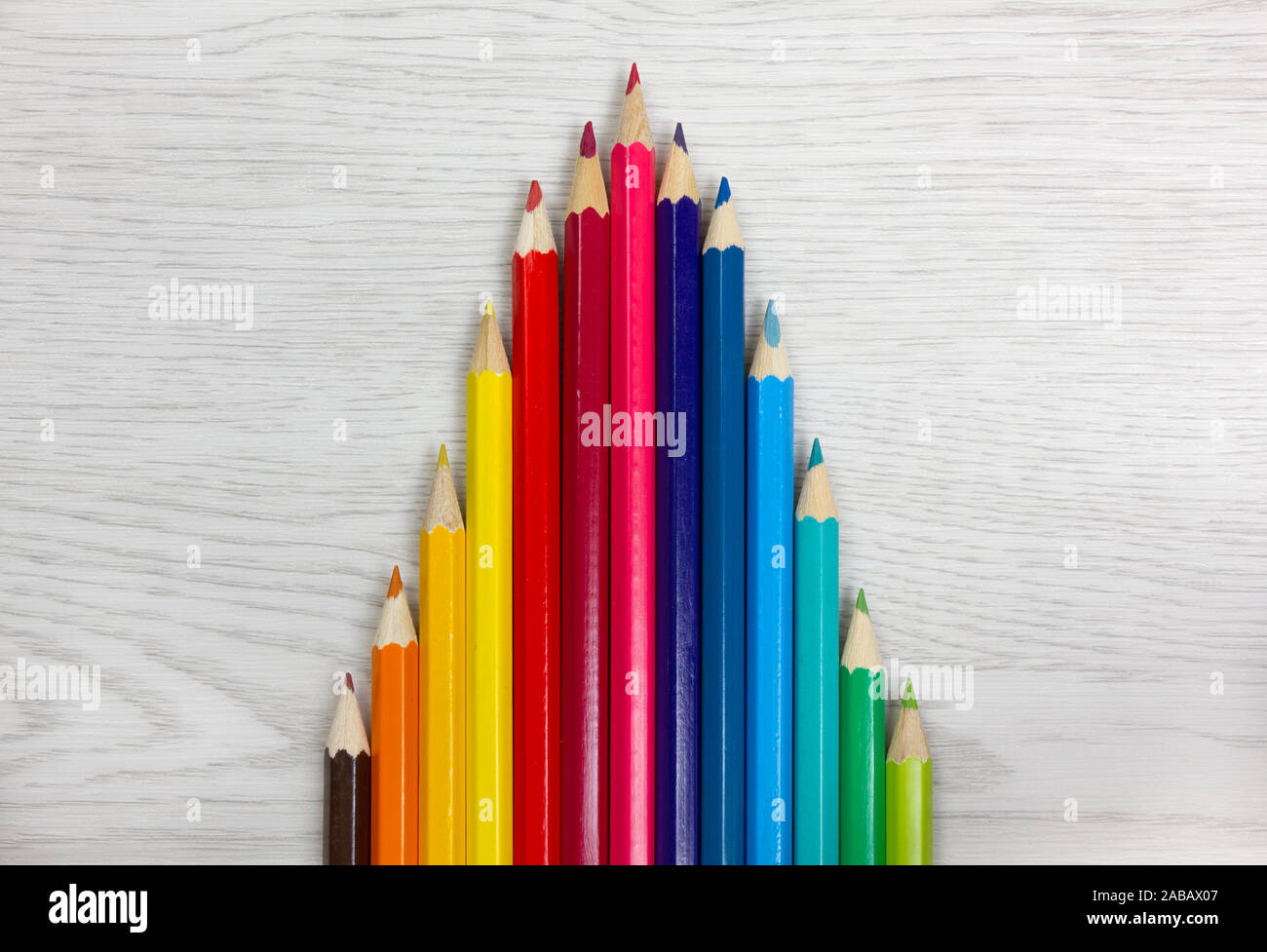 Serie von Buntstiften auf weißem Holz Hintergrund platziert, so dass eine Glockenkurve Graphen zeichnen Stockfoto