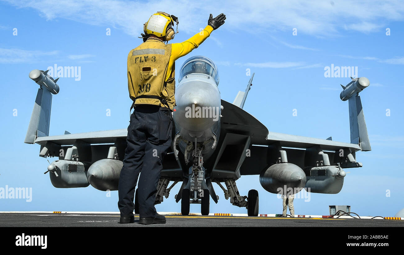 U.S. Navy Aviation Boatswains Mate 3. Klasse Derek Riley Signale an der Pilot eines E/A-18G Growler elektronische Kampfjet für Take off aus dem Flight Deck der Nimitz-Klasse Flugzeugträger USS Theodore Roosevelt während Operationen November 22, 2019 im östlichen Pazifik. Stockfoto