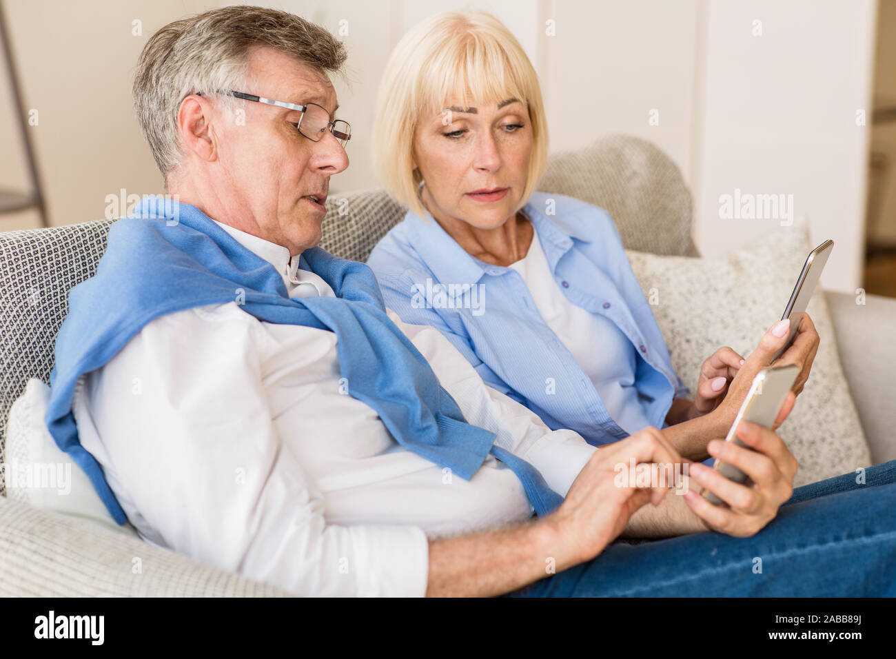 Moderne Großeltern. Senior Paar mit Handys zu Hause Stockfoto