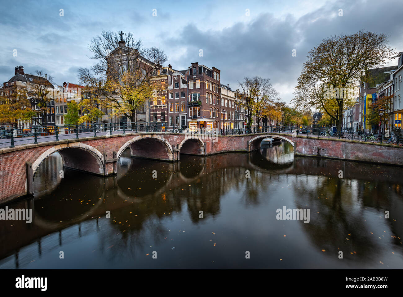 Nacht Blick auf Amsterdam Stadtbild mit Canal, die Brücke und die mittelalterlichen Häuser in der Dämmerung beleuchtet. Amsterdam, Niederlande Stockfoto