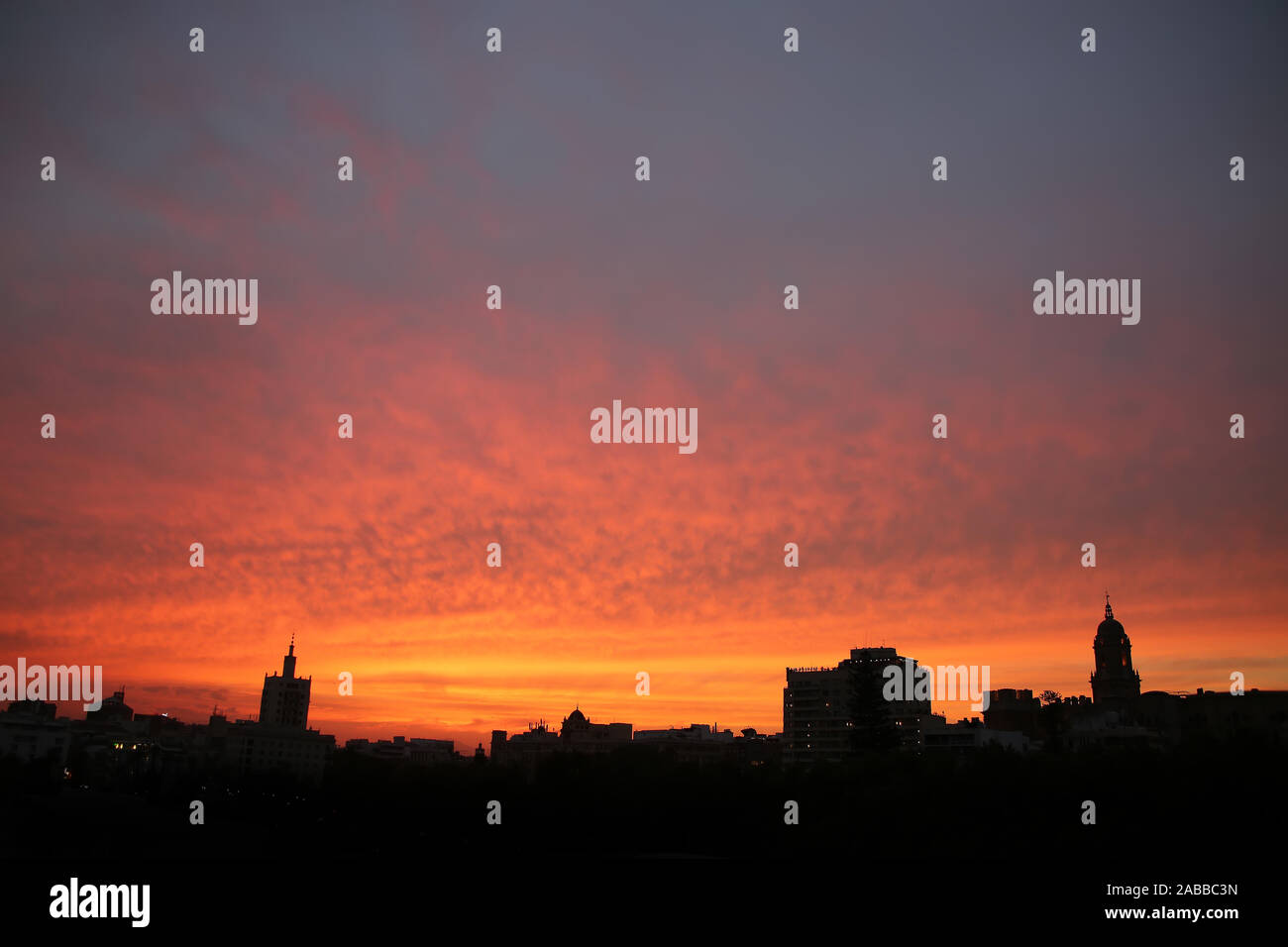 Schönen bunten Sonnenuntergang Himmel über die Skyline und die Dächer der Stadt, mit dem Gebäude als Silhouette, Malaga, Andalusien, Südspanien. Stockfoto
