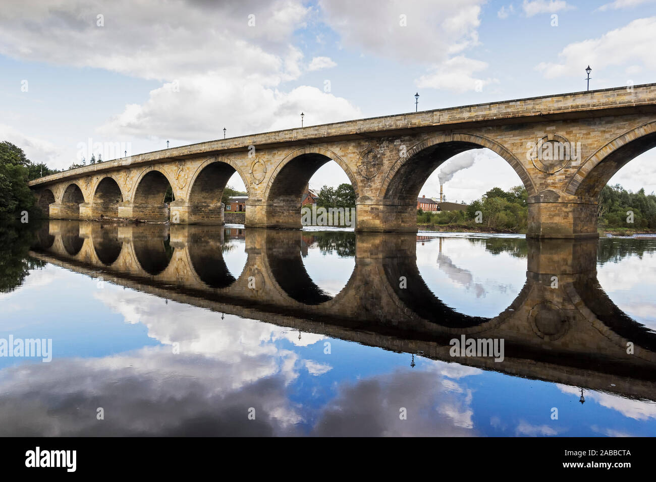 Hexham denkmalgeschützten Steinbogenbrücke in Northumberland, Großbritannien mit Egger UK Spanplattenfabrik sichtbar durch einen Bogen. Stockfoto