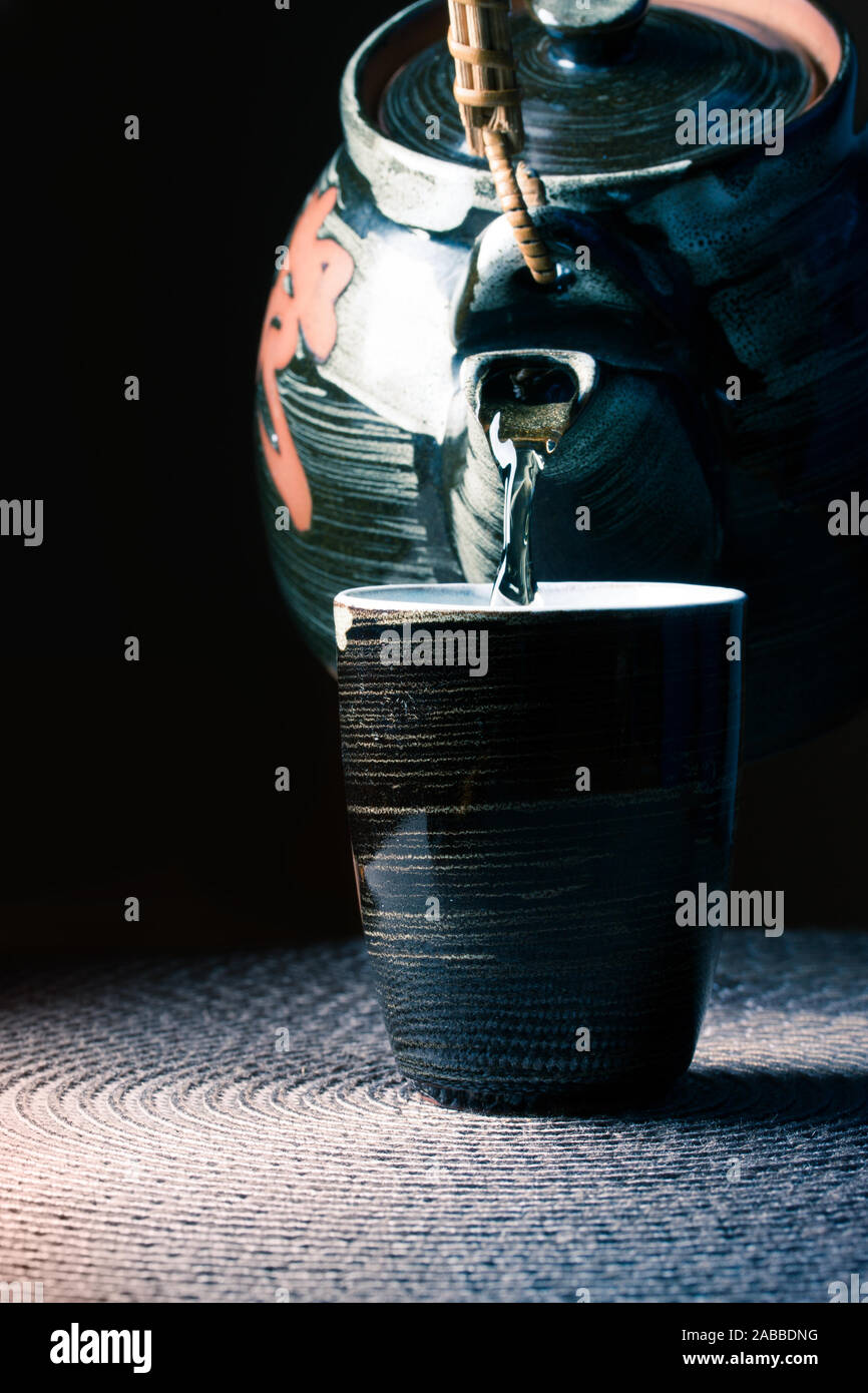 Leicht oolong grüner Tee gießt aus einem dunklen Teekanne in einem kleinen chinesischen Tee Tasse gießen Stockfoto