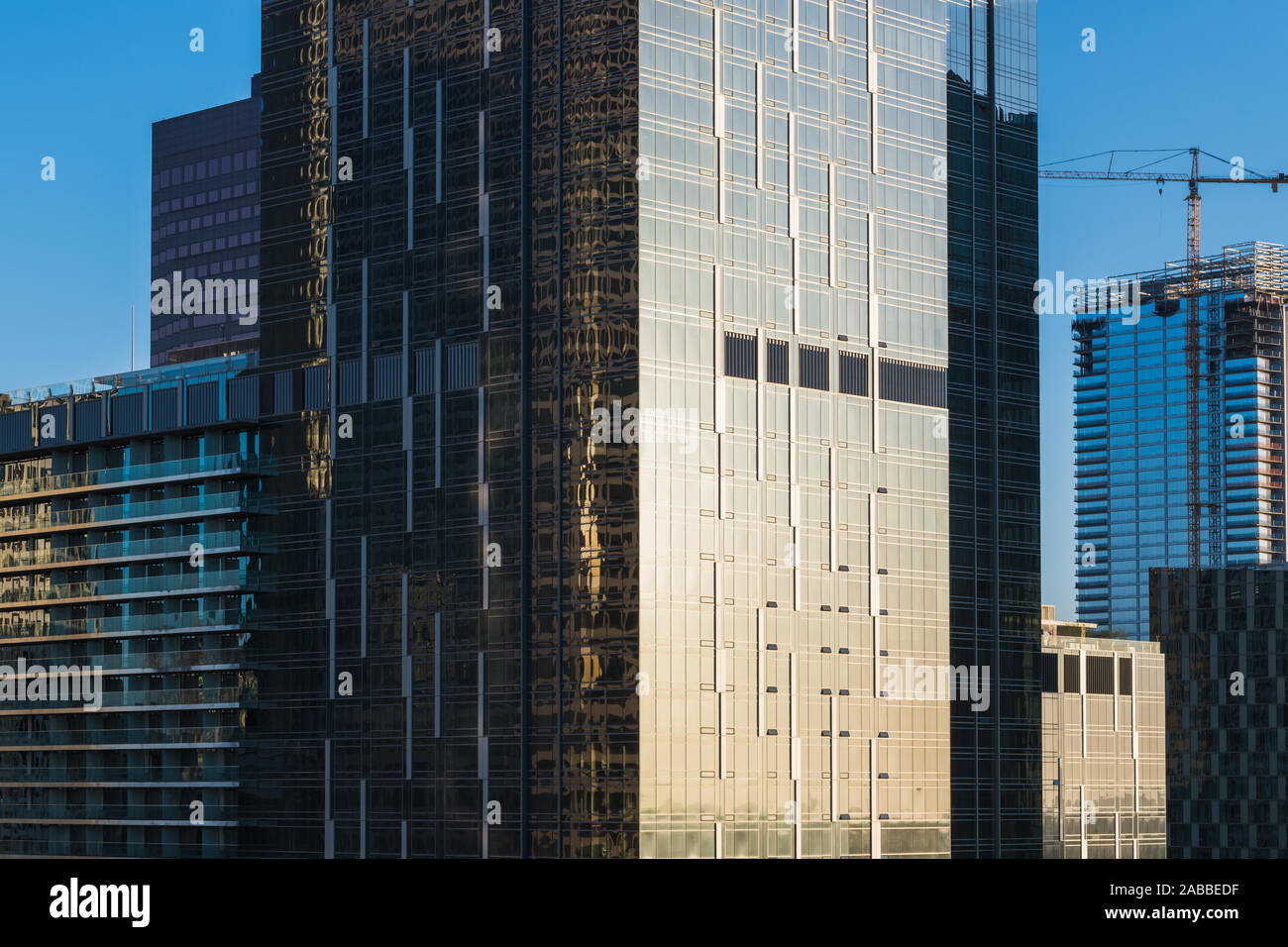 Nahaufnahme eines dichten Stadtbild aus Glas und Stahl Büro- und Wohngebäuden Türme und ein Baukran reflektiert das Licht des Sonnenuntergangs in Downtow Stockfoto