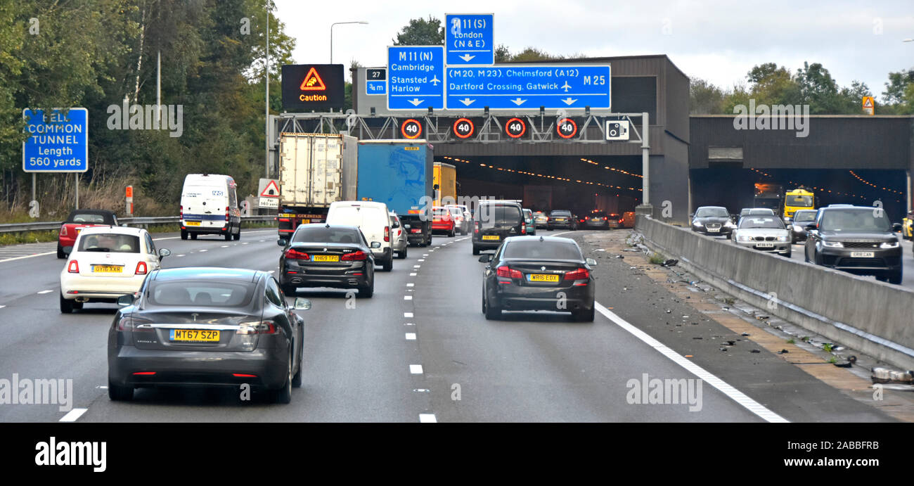 Autobahn M25: Verkehrslärm auf der Autobahn und zahlreiche Schilder am vierspurigen Eingang des Bell Common Tunnel mit variablem 40 km/h-Geschwindigkeitsschild Essex England UK Stockfoto